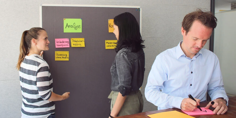 Menschen planen Kommunikationsprojekte an einer Pinnwand